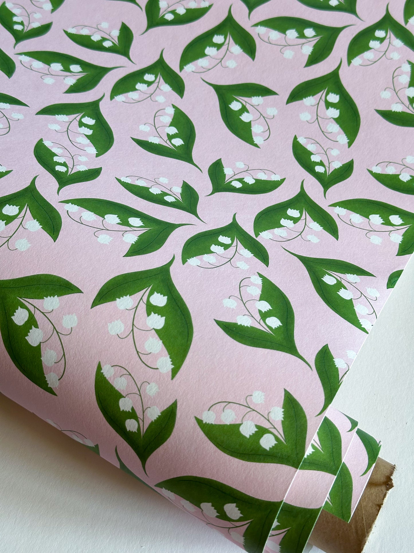 Close-up of pink lily of the valley floral wallpaper roll by Reka Thornton